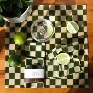 green checkers beeswax wraps 3 pack in natural light with limes and houseplant
