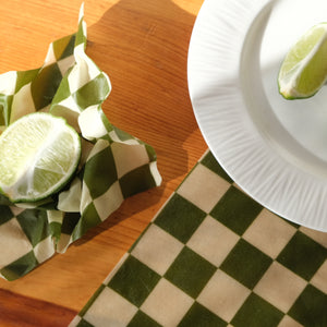 green checkers beeswax wrap with limes on wood countertop
